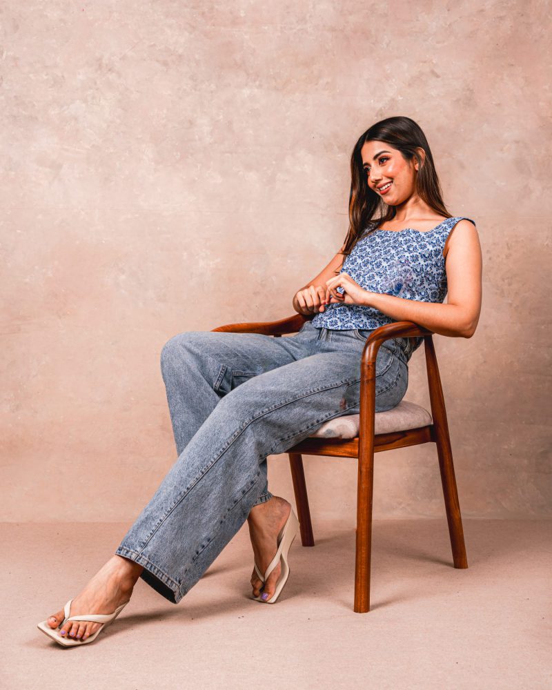 Seated model in an indigo tank and straight jeans