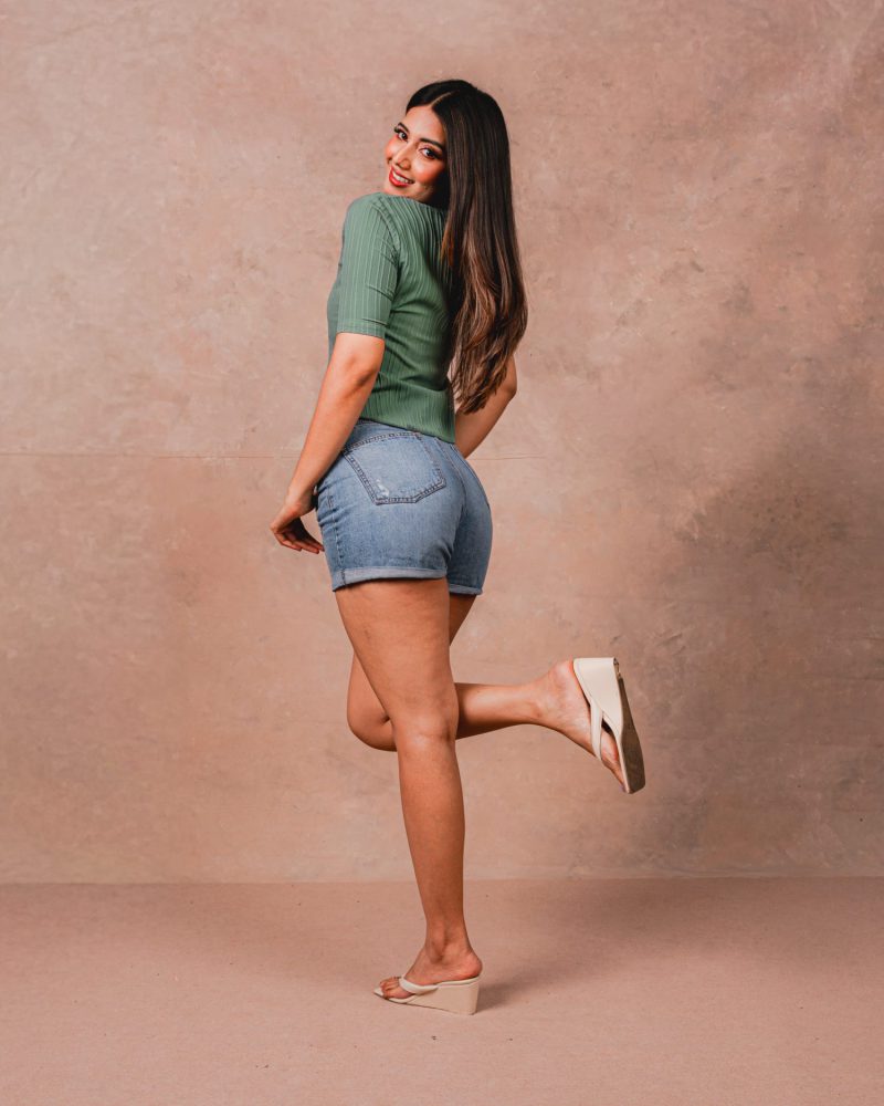 Model in a ribbed sage top and denim shorts